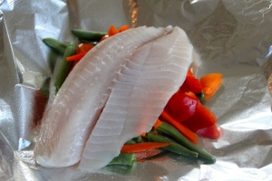 Add one of your tilapia filets on top of your veggies.
